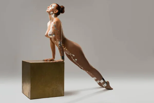 Naken smal kvinna med kroppskonst i studio — Stockfoto