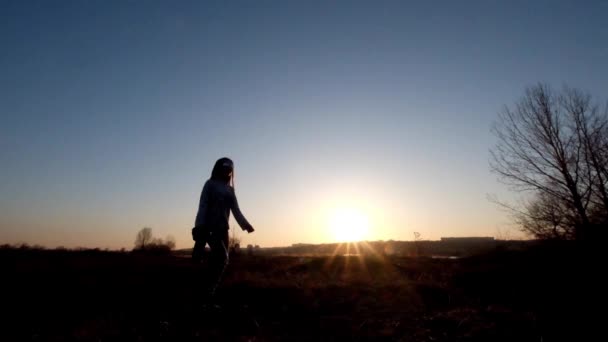 Silhouet van een jonge meisje-fotograaf bij zonsondergang — Stockvideo