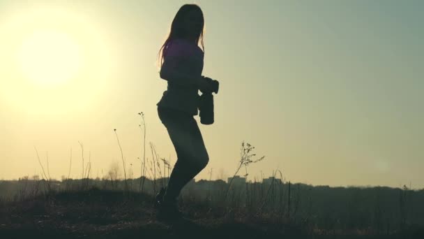 Silhouet van een jonge meisje-fotograaf die een foto's neemt — Stockvideo