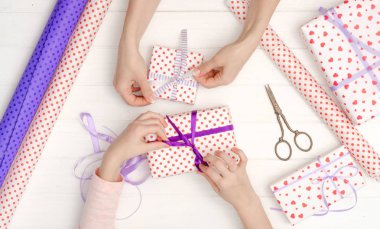 Kız hediyeye kurdele bağlamış.