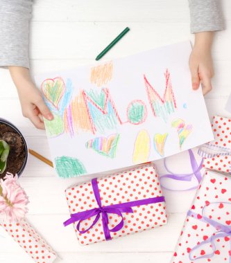 Küçük kız mutlu anne kutlama günü için Craft kartı tutan