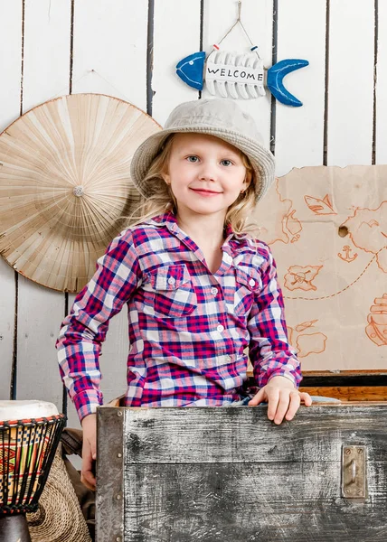 Linda niña en sombrero sentado en el pecho —  Fotos de Stock
