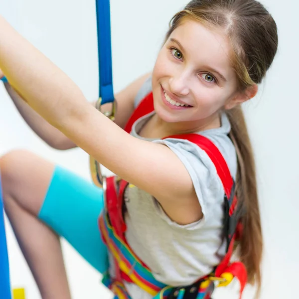 Active little girl in safety harness on climbing wall — Stock Photo, Image