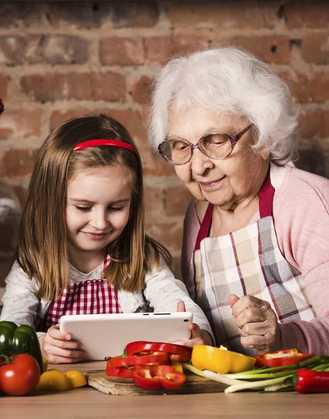 孙女和祖母与片剂在厨房 — 图库照片