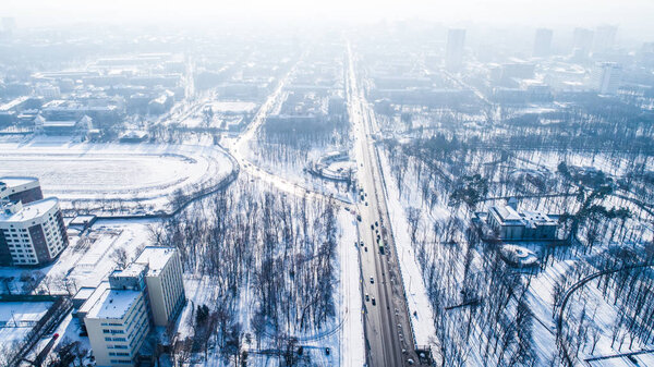 Aerial view on city in winter day. City panorama with straight road covered with snow from a bird eye view