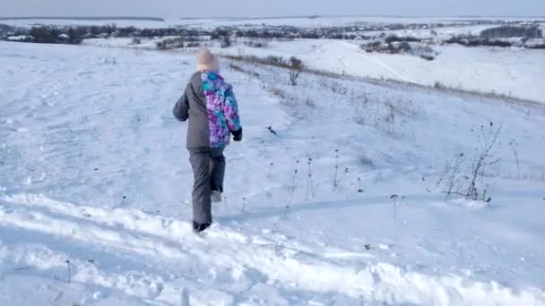 Маленькая девочка счастливо бежит по снегу — стоковое видео