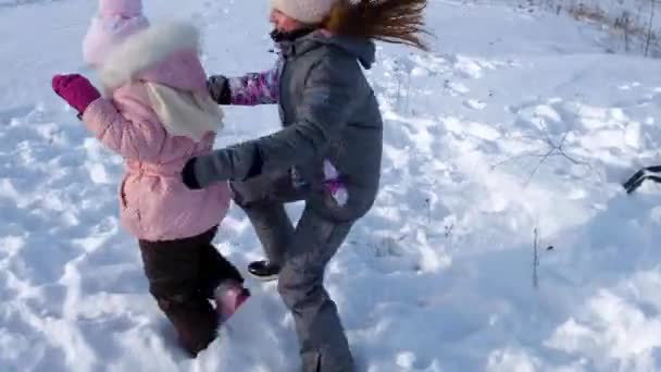 Dos hermanas pequeñas caen en la nieve y se divierten — Vídeos de Stock