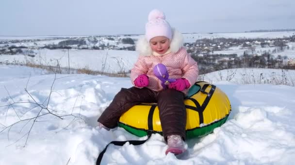 Ragazzina fa palle di neve seduto su tubi — Video Stock