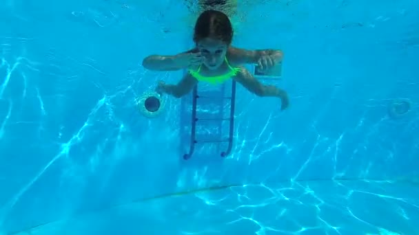 Маленька дівчинка плаває під водою у басейні — стокове відео