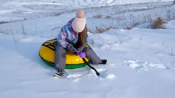 Маленькая девочка делает снежки сидя на трубах — стоковое видео