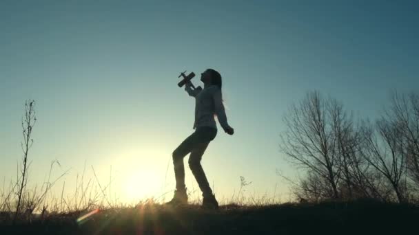 Silhouette eines fröhlichen Mädchens, das mit Spielzeugflugzeug spielt — Stockvideo