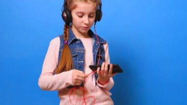 Küçük bir kız kulaklık telefona bağlanan ve müzik hoşlanır