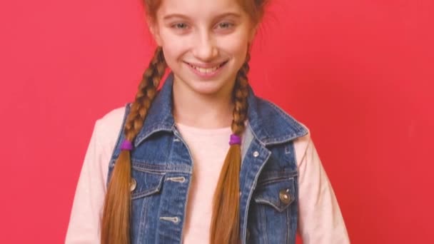Мила дівчинка посміхається на червоному тлі — стокове відео