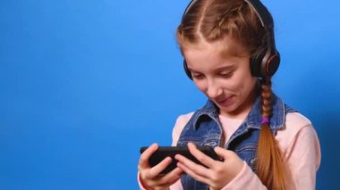 Küçük kız onu Smartphone'da bilgisayar oyunu oynamak kulaklık