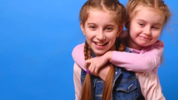 A little girl is riding on her sisters back — Stock Video