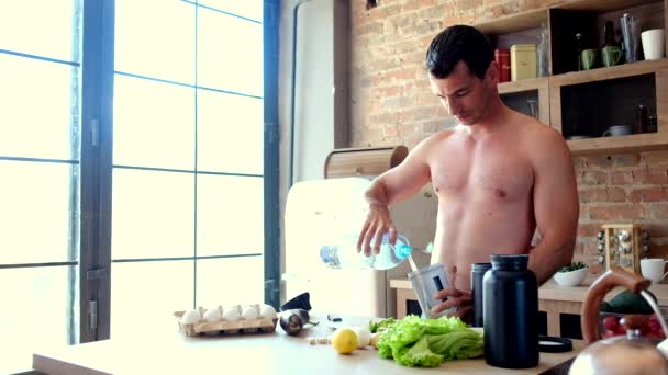 Homem cozinha um cocktail de proteína na cozinha — Vídeo de Stock