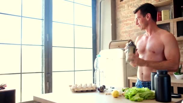 Человек готовит протеиновый коктейль на кухне — стоковое видео