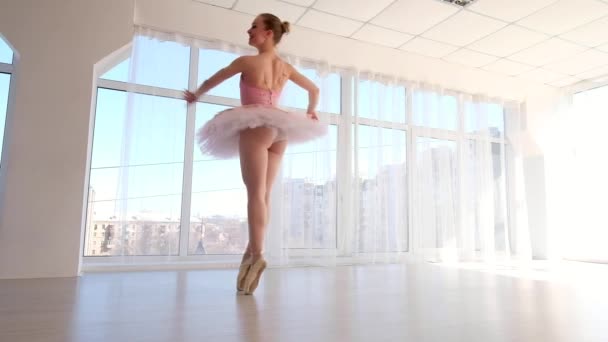 Atraktivní žena baletku v růžové sukénce cvičí a usmívá se