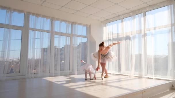 Jonge elegante ballerina leert haar dochtertje dansen in studio — Stockvideo