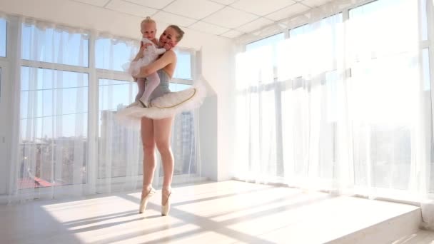 Madre en traje de ballet de pie de puntillas y sosteniendo en las manos hija pequeña — Vídeos de Stock