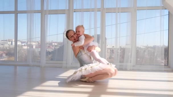 Joven madre abrazando a la pequeña hija sonriente en el estudio de ballet — Vídeos de Stock