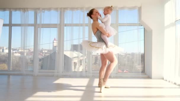 Балерина танцовщица стоя на цыпочках и держа на руках свою маленькую дочь — стоковое видео