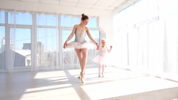 Madre en traje de ballet cogida de la mano de su hija pequeña mientras salta — Vídeo de stock