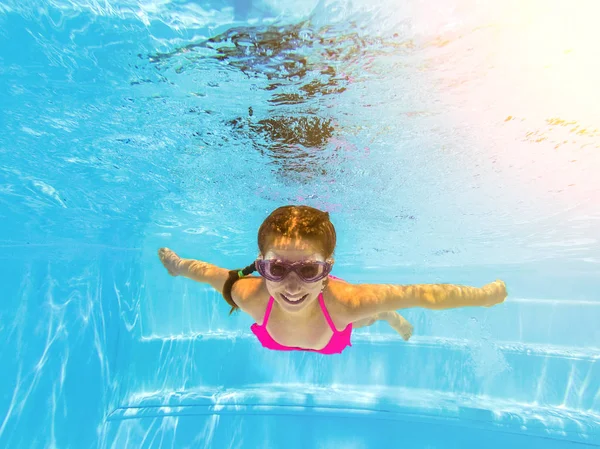 Usmívající se dívka, plavání pod vodou v bazénu — Stock fotografie