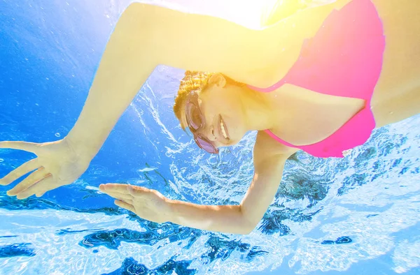 Улыбающаяся девушка плавает под водой в бассейне — стоковое фото