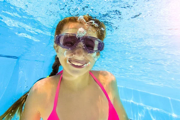プールで水中を泳いでいる少女の笑みを浮かべてください。 — ストック写真