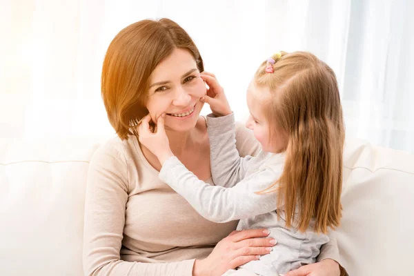 Ei lita jente som sitter med mamma og lager grimaser – stockfoto