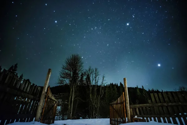 Wooden fence in mountains with starry sky above
