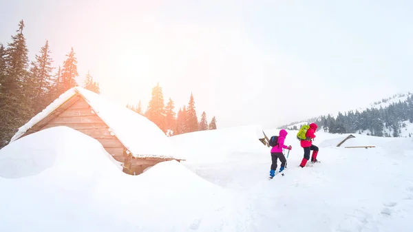 Escursionisti che vanno in una vecchia capanna coperta di neve — Foto Stock