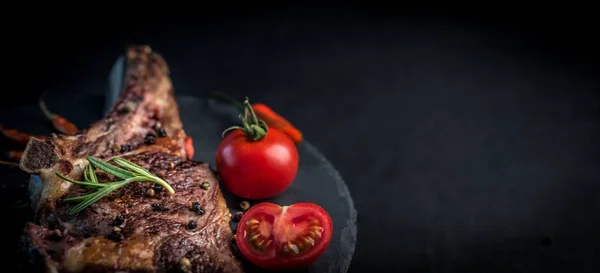 Grilled beef steak on bone with tomatoes — Stock Photo, Image