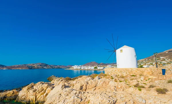 Old white windmill on the cliff in front of water, Greece — Stock Photo, Image