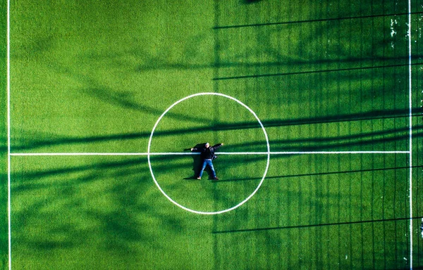 Uomo sdraiato al centro del campo di calcio, vista dall'alto — Foto Stock