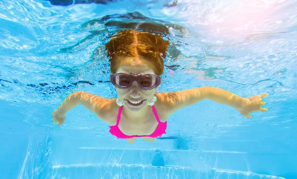 Sonriente chica nadando bajo el agua en la piscina — Foto de Stock