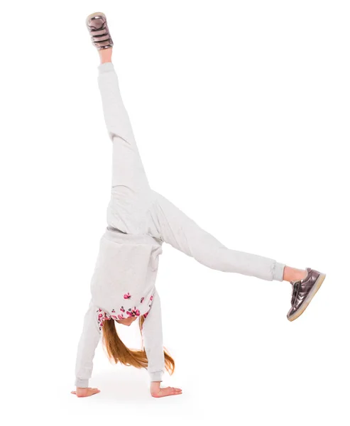 Petite fille active sur fond blanc faisant un handstand — Photo