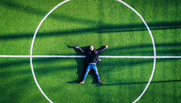 Hombre acostado en el centro del campo de fútbol, vista superior — Foto de Stock