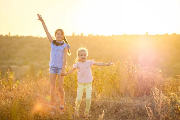 Маленькие улыбающиеся девочки стоят с радостными поднятыми руками — стоковое фото