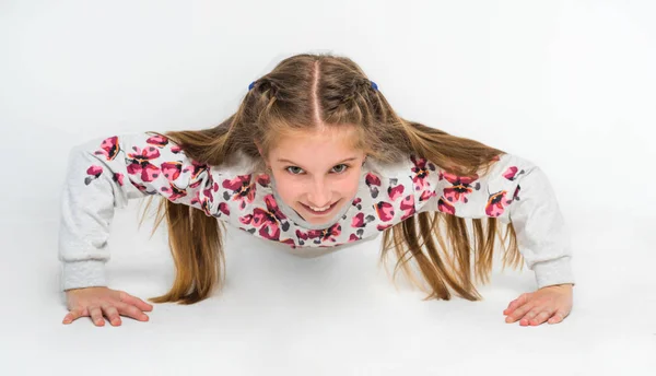 Little girl doing push-ups on light background — Stock Photo, Image
