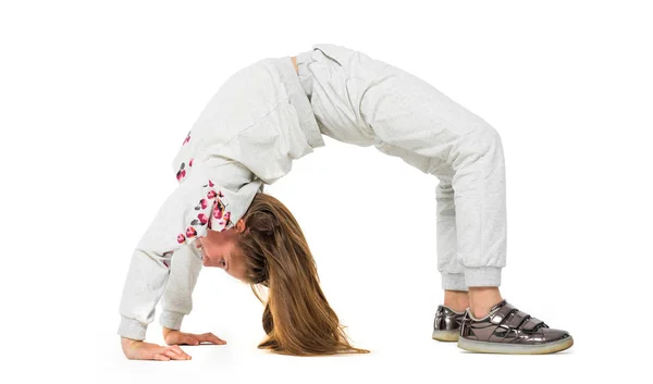 Kleines Mädchen überbrückt Position auf hellem Hintergrund — Stockfoto