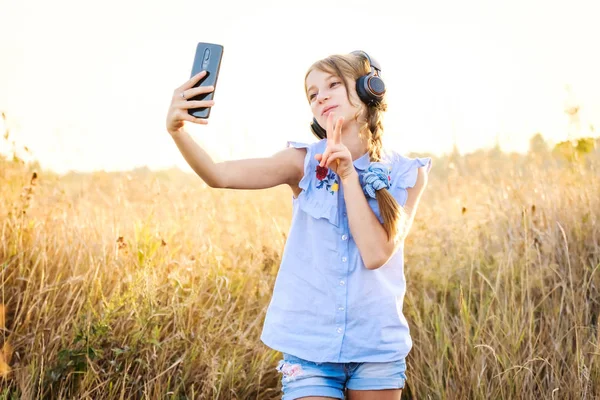 Dospívající dívka se sluchátky s roztomilý selfie — Stock fotografie