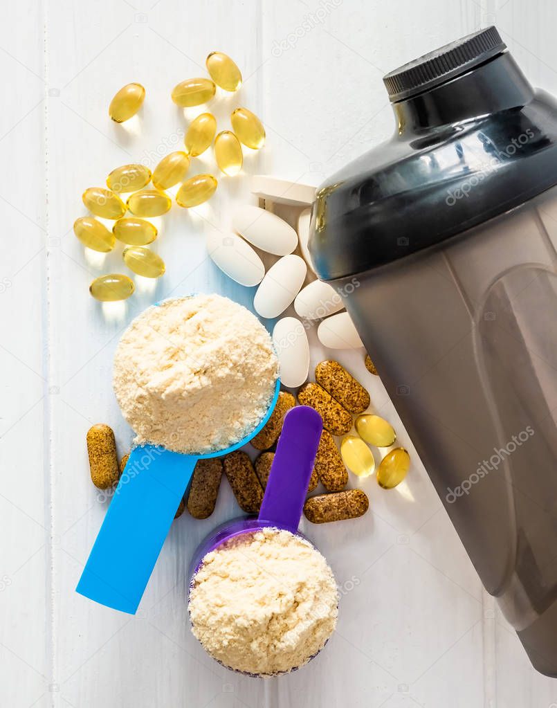 Sport Pills,vitamins and protein powder with brown bottle composed on the white table