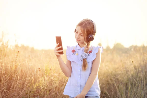 Menina adolescente com fones de ouvido segurando smartphone em uma mão — Fotografia de Stock
