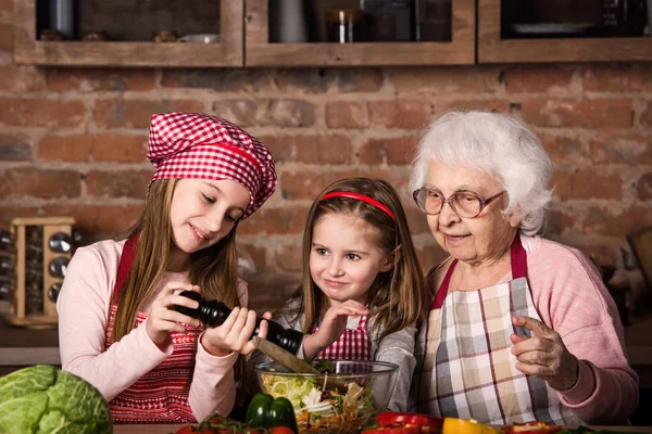 Sestry pomáhají babička připravit salát — Stock fotografie