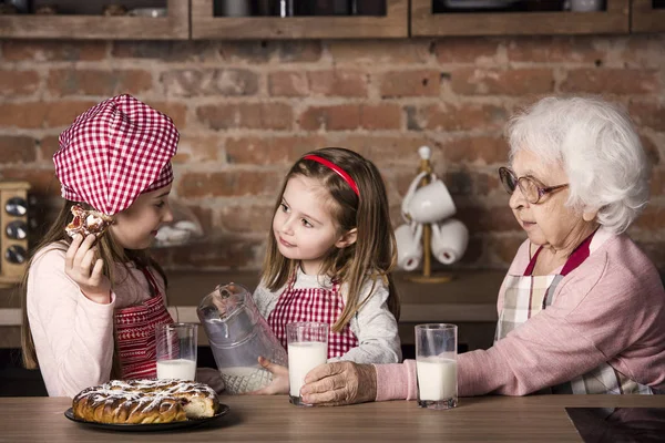 Starší žena s vnoučaty usmívala a ochutnávku koláč — Stock fotografie