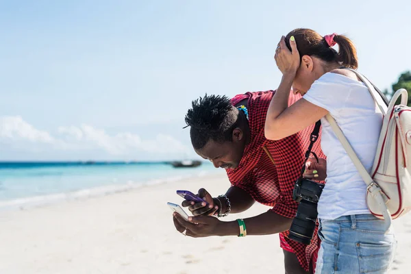 Černý muž a žena při pohledu na telefony, zanzibar — Stock fotografie