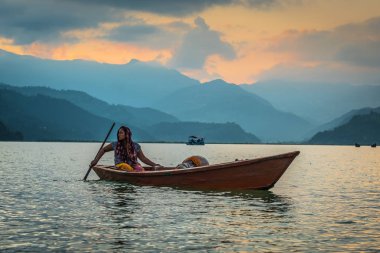 Gün batımında, Pokhara, Nepal gölde bir teknede kadın