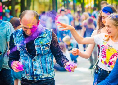 İnsanlar bayramı kutlarken renkli boya serperler.